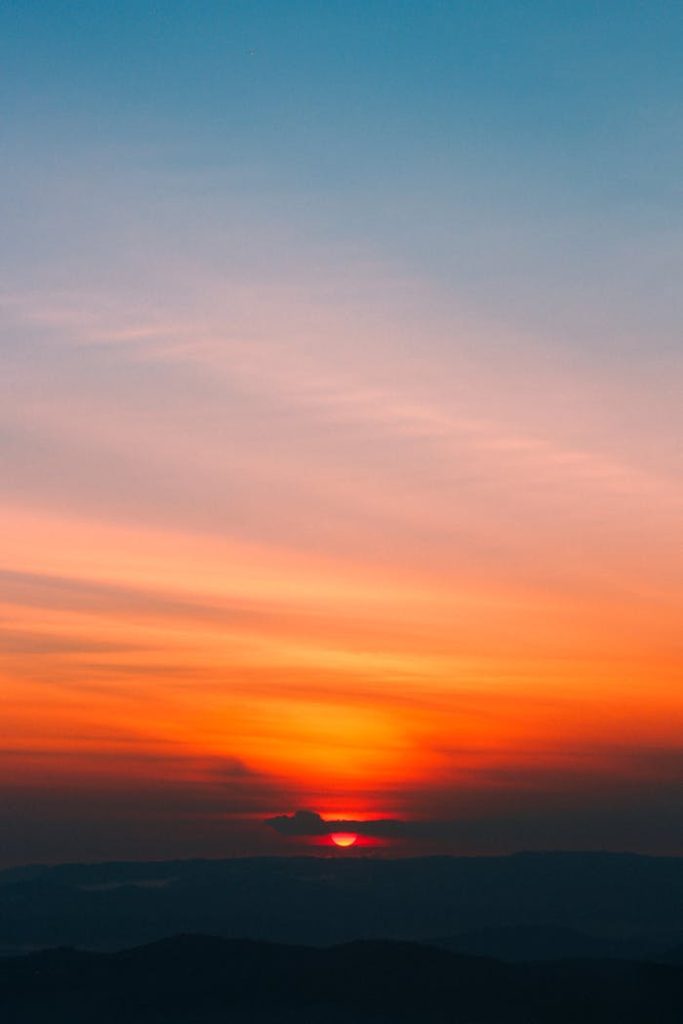 Dramatic sunrise with vibrant orange and blue hues painting the sky, creating a serene and peaceful scene.